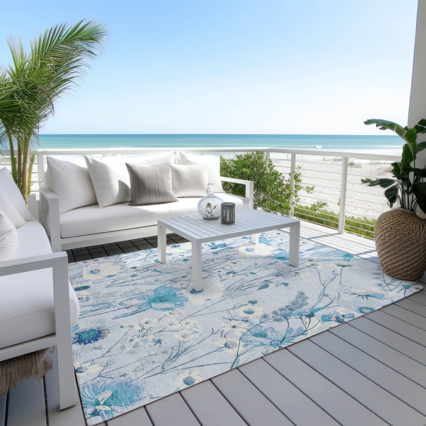 Homeroots sky blue floral washable area rug on beachside deck with white outdoor sofa and coffee table